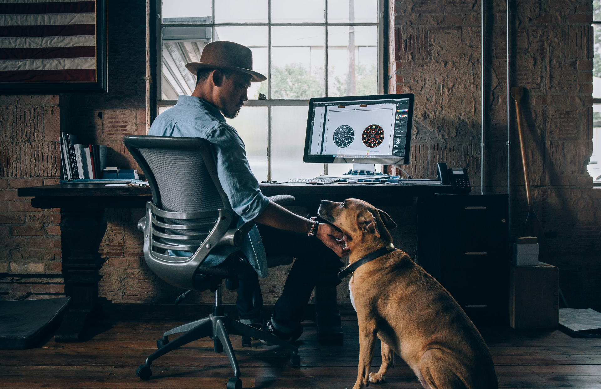 Man working at desk with dog by his side in a warm loft space